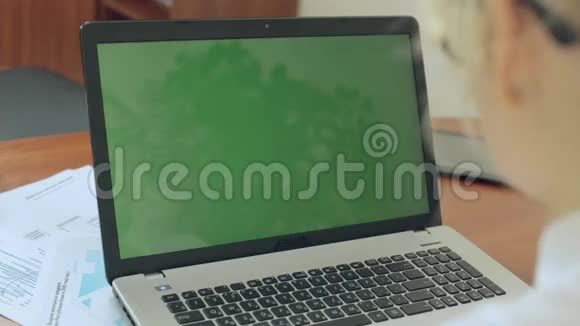 那个女孩坐在笔记本电脑后面带着绿色的屏幕视频的预览图