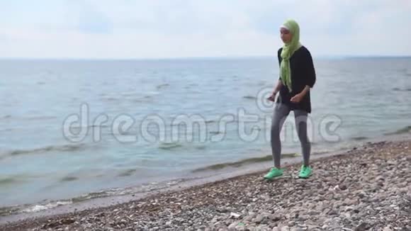 一位身穿罩袍和运动鞋的年轻穆斯林妇女正在海上奔跑视频的预览图