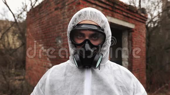 穿着生物危险服和防毒面具的人直视着摄像机视频的预览图