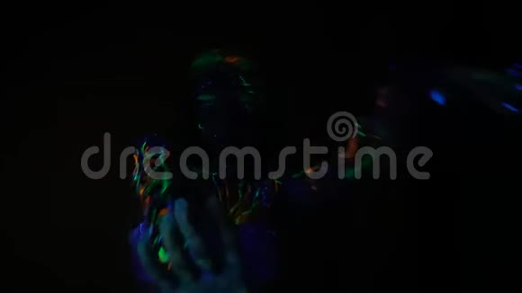 一个穿着花纹的漂亮姑娘在黑暗中的日光灯下轻轻地跳舞视频的预览图
