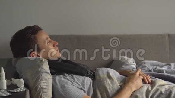 一个男人躺在床上躺在家里的药品旁边喉咙里喷了一剂喷雾剂视频的预览图