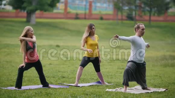 男人和女人公园里的运动员在绿色公园户外做瑜伽运动视频的预览图