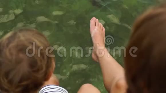慢动作稳定镜头女人和她的儿子坐在海上的木步道上玩视频的预览图