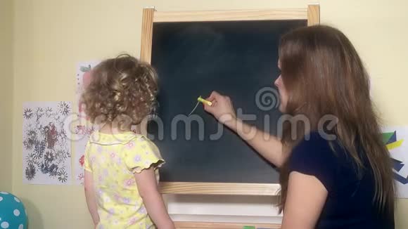 女老师给小女孩用粉笔在黑板上写数字视频的预览图