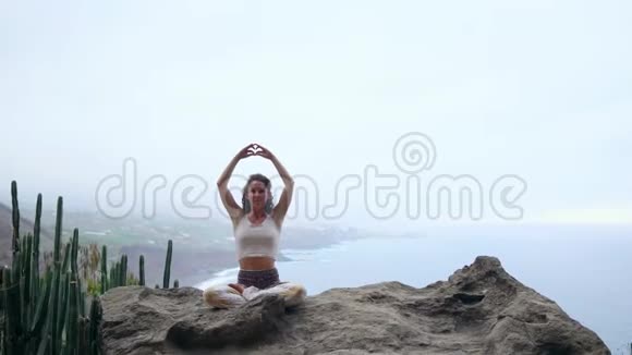 一个坐在山顶上的女人沉思着用手做了一个手势玛哈萨卡尔反对海洋和视频的预览图