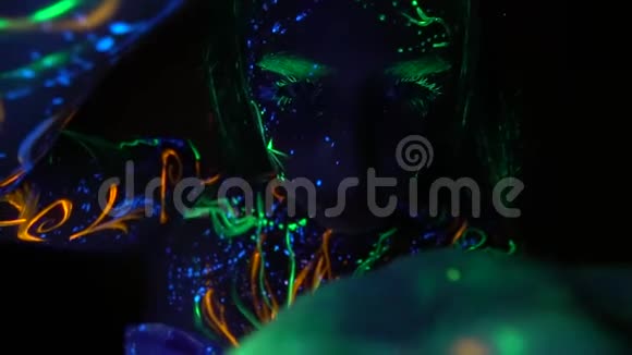 一个女孩她的头发睫毛和身体上的图案在黑暗中发光把相机打开视频的预览图