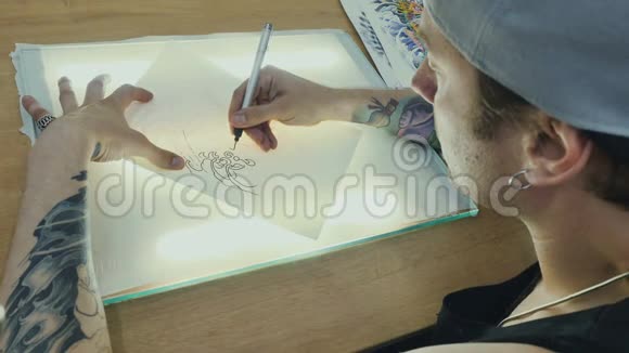纹身师用光线在玻璃上的描画纸上画出草图视频的预览图