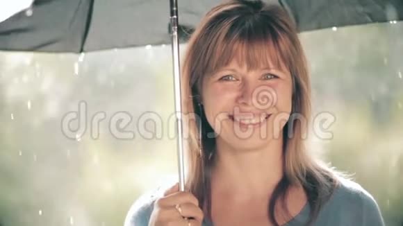 美丽的女人站在雨中的伞下真诚地微笑享受大自然视频的预览图