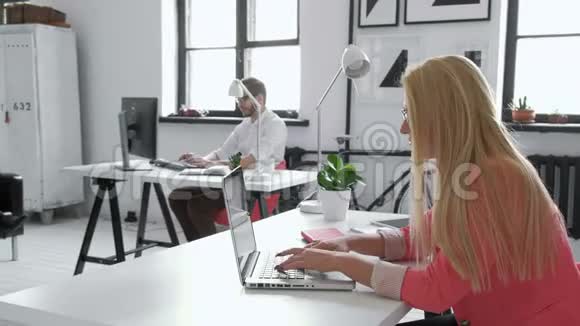 一位20的金发女性商业伙伴坐在电脑前整洁的玻璃办公桌前的画像视频的预览图