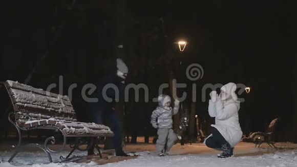父亲和小女儿慢吞吞地把雪扔给一个年轻的女人视频的预览图