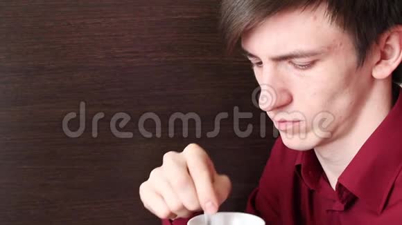 一个年轻人手里拿着一个橙色的杯子搅动着一茶匙看着喉咙和一个杯子视频的预览图