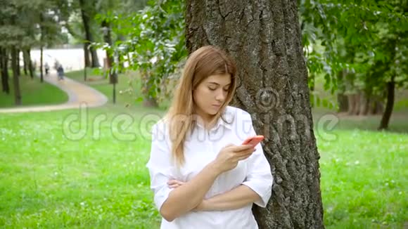 女孩在夏季公园使用智能手机视频的预览图