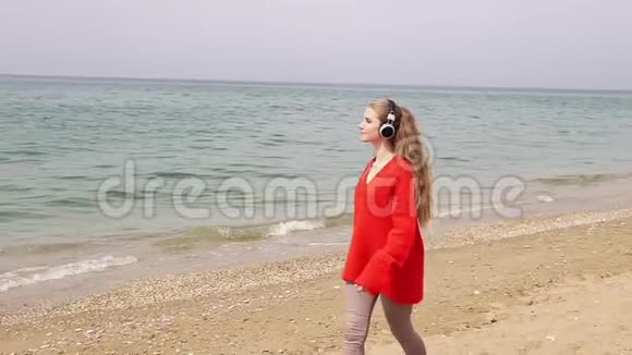 在海边的海滩上女人用大耳机听音乐视频的预览图