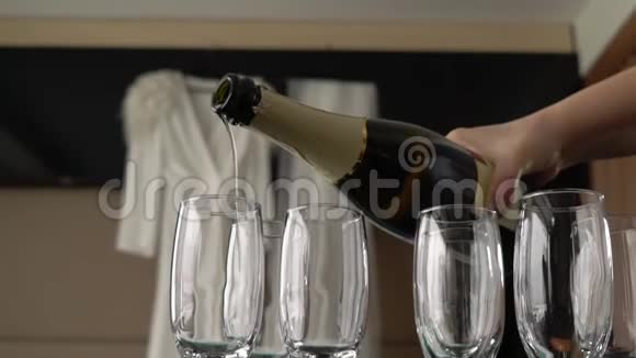 把香槟从瓶子里倒进桌子边的空杯子里视频的预览图