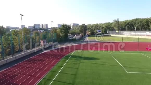 空中拍摄一名独自一人的运动员沿着流过足球场的小溪奔跑视频的预览图
