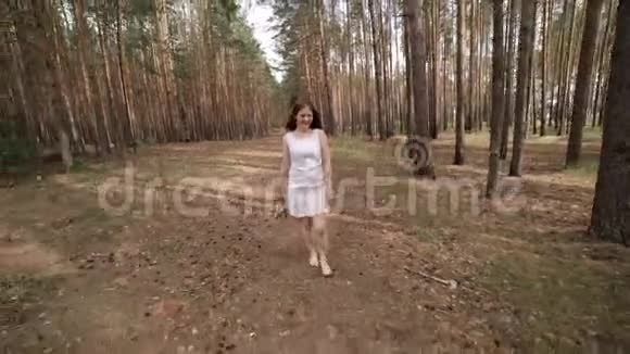 一个穿白衣服的女孩正在树林里散步视频的预览图