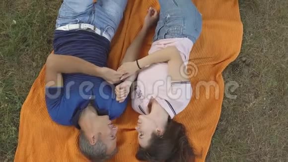 爱情情侣躺在橙色格子布上俯视视频的预览图
