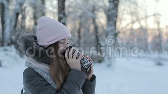 女孩喝热茶或咖啡从节日杯与雪上公园视频的预览图
