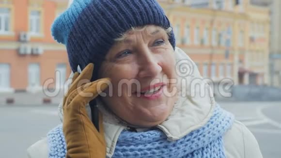 一位老年妇女在市区街头愉快地打电话视频的预览图