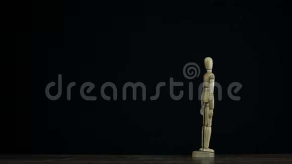 在黑色背景支架上的工作室中停止运动的木制人物假人并旋转以获得头衔视频的预览图