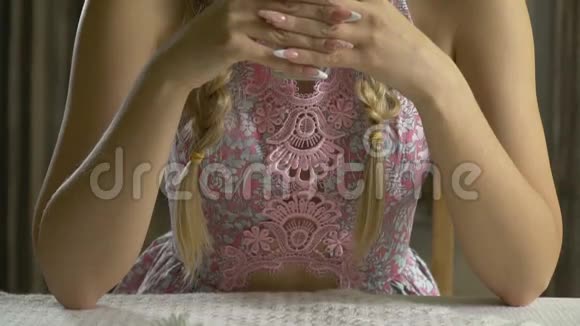 一个穿着连衣裙的女人坐在桌前嘴里含着洋甘菊视频的预览图