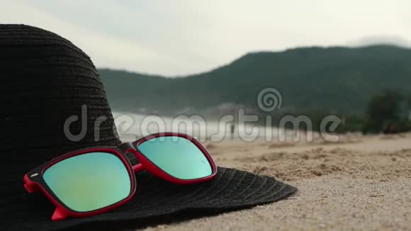 太阳镜和黑色宽边躺在沙子上戴着墨镜反射着大海海浪和天空视频的预览图