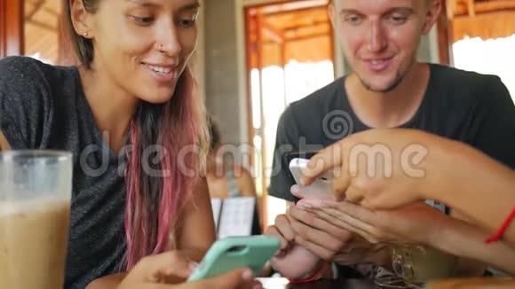 年轻女孩在坐在咖啡厅的手机上展示朋友的照片泰国视频的预览图