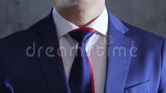 穿蓝色西装的人的手臂在灰色混凝土墙的背景上将领带系在脖子上视频的预览图