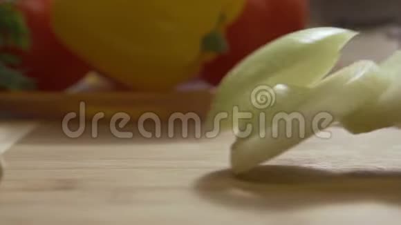在木切割板上掉落的环状洋葱玻璃碗上切下的葱花圈的特写视频的预览图