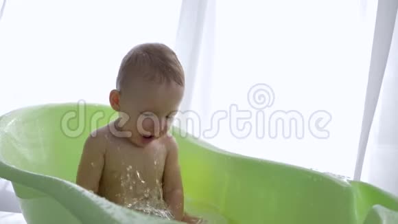 快乐的学步男孩洗澡时泼水视频的预览图