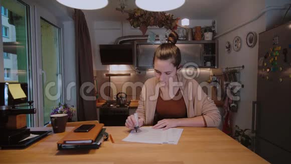 年轻的女商人拿着文件坐在桌子旁拿着文件工作在家加班工作视频的预览图
