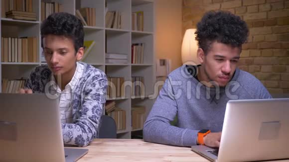 印度和非裔美国男学生使用笔记本电脑并在室内在线学习的特写镜头视频的预览图