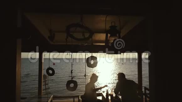 在豪华餐厅的海滩上享用浪漫的晚餐两人在蜜月时在日落时喝热带鸡尾酒慢慢慢慢视频的预览图