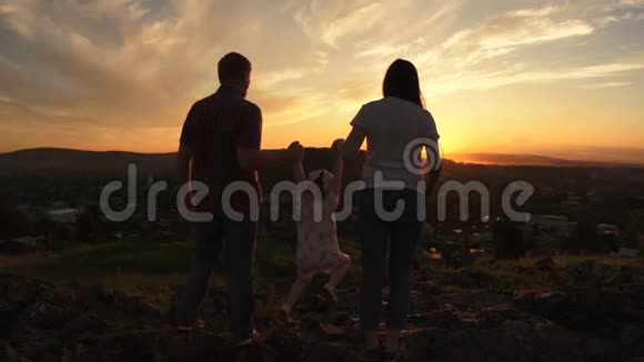 一个夏天的晚上一家人正站在日落的山上视频的预览图