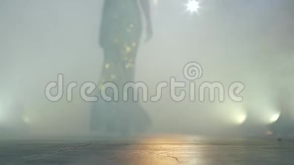 为穿高跟鞋的女人展示新的蕾丝连衣裙在薄雾中走上舞台视频的预览图