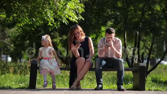 一家人坐在有智能手机的长椅上视频的预览图