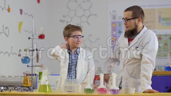 实验室助理和他的学生看着实验室里热气腾腾的烧瓶视频的预览图