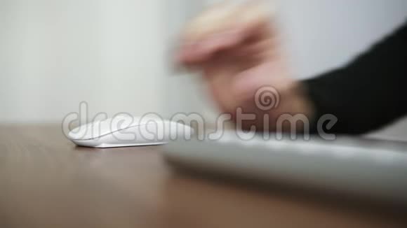 一个年轻人用无线电脑鼠标坐办公室的桌子旁木制桌桌视频的预览图