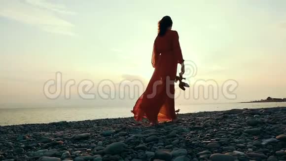 夏天日落时分在沙滩上散步的女人视频的预览图