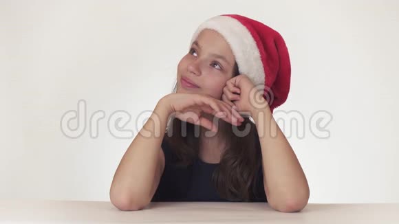 美丽快乐的少女戴着圣诞老人的帽子梦想着礼物在盒子里收到节日蛋糕和礼物但表达了视频的预览图