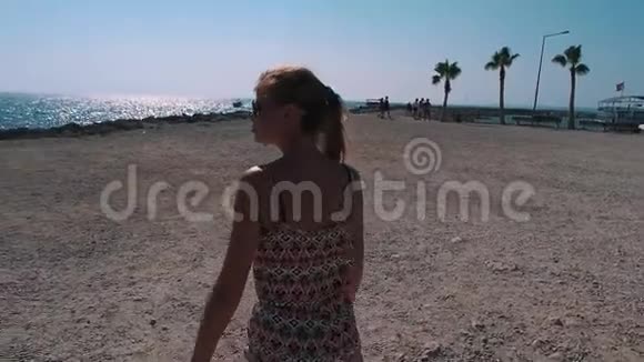 一个女孩带着棕榈树沿着海岸线散步视频的预览图