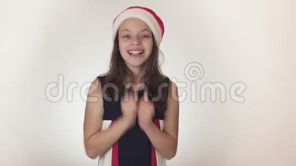 戴着圣诞老人帽子的漂亮快乐少女在白色背景的股票镜头中进行情感想象和摆姿势视频的预览图