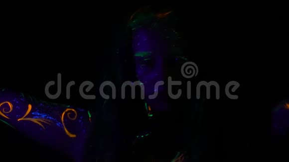 神秘的女孩在黑暗中跳着荧光颜料的图案视频的预览图