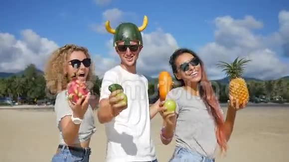 三个年轻的朋友在海滩上疯狂和异国情调的泰国水果跳舞纯素舞蹈泰国范甘高清高清视频的预览图