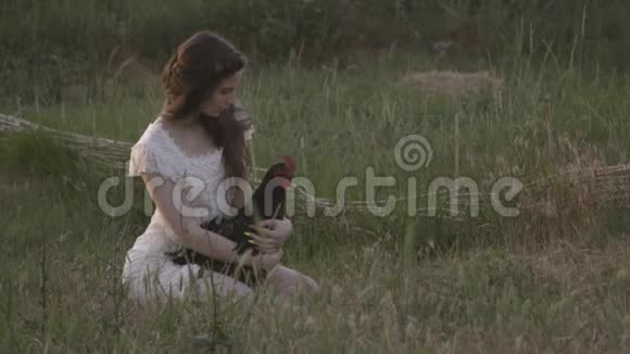 穿着白色连衣裙的性感的布鲁内特与公鸡在她的膝盖上视频的预览图