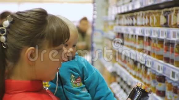 可爱的白种人妇女选择婴儿食品在超市抱着婴儿怀里妈妈的特写镜头视频的预览图
