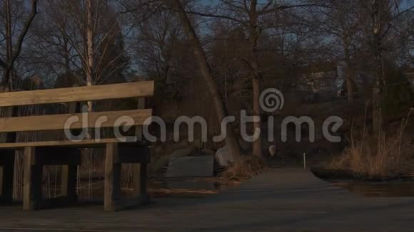 金色的夕阳在湖边露出一张长凳和一个木制甲板视频的预览图
