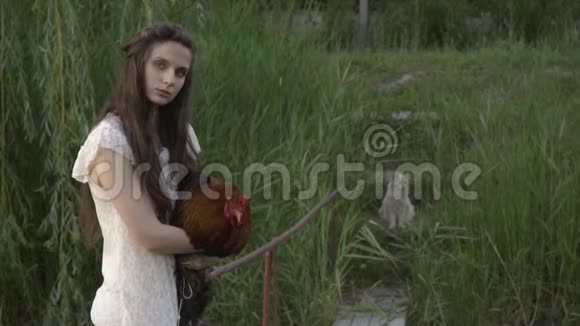 穿着白色衣服的黑发女人在木桥上猫坐在草丛里视频的预览图