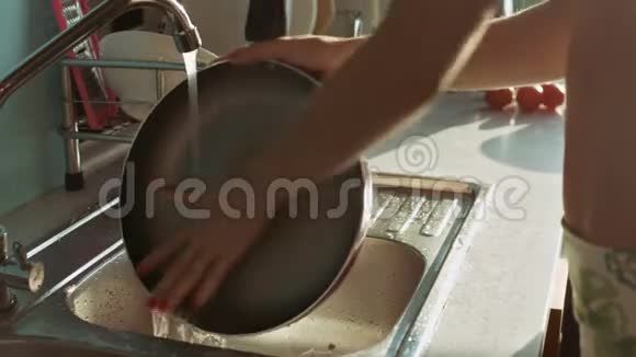 女人透过窗户在阳光下冲洗盘子视频的预览图
