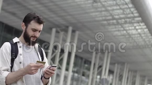 一个满脸胡须的男人拿着背包走路检查他的信用卡视频的预览图